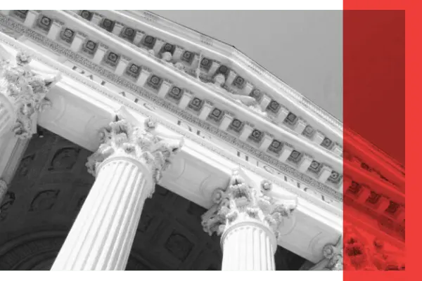 A black and white image of the pillars of a courthouse exterior.